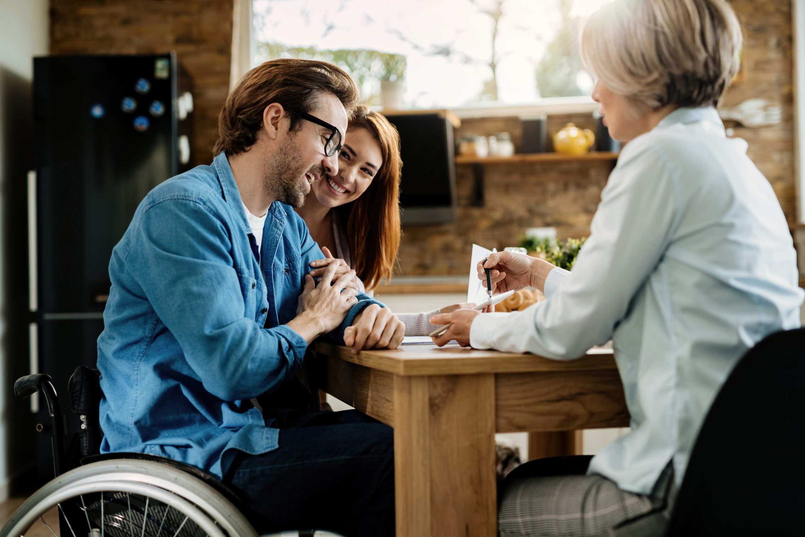 Happy man in wheelchair and his wife having a meeting with insur
